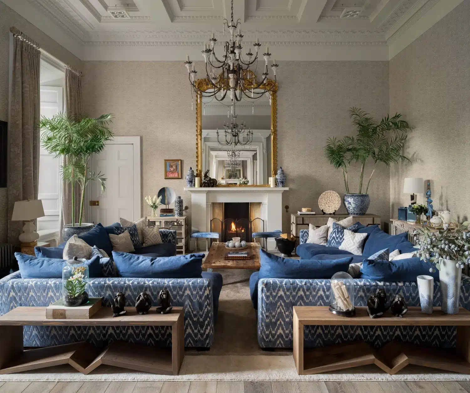 Elegant living room by Jeffreys Interiors with blue sofas, statement chandelier, fireplace, and decorative accents