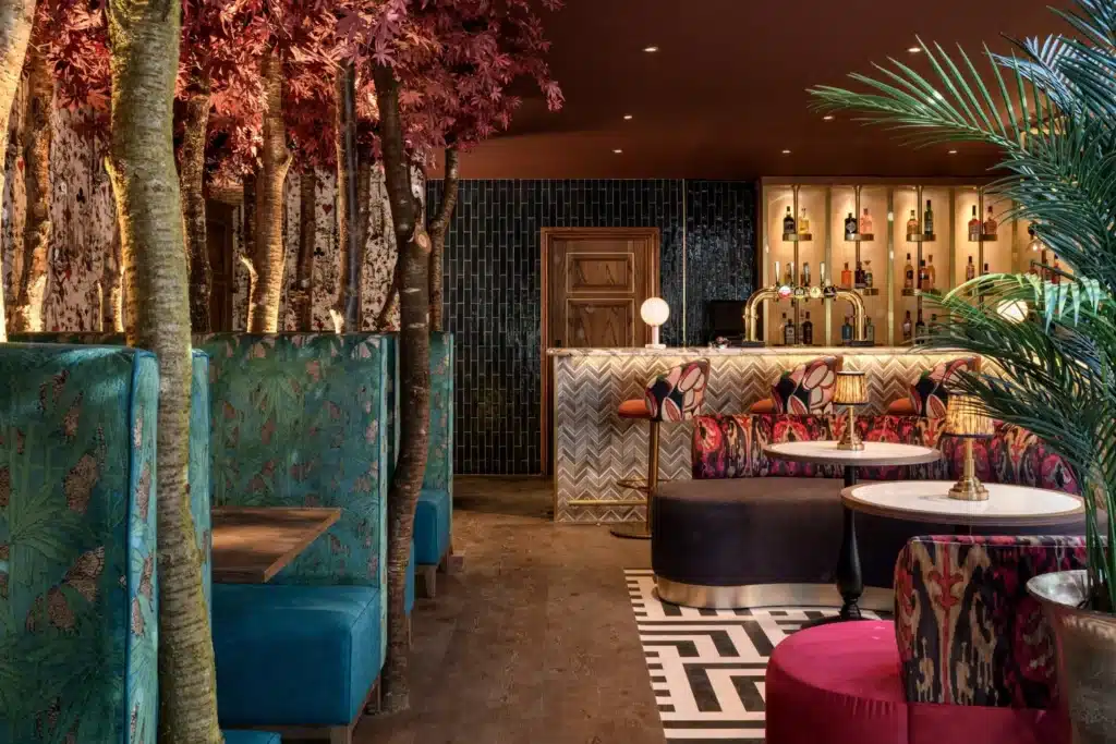 Vibrant bar and lounge interior with patterned seating, bold colors, and tree-inspired design by Jeffreys Interiors